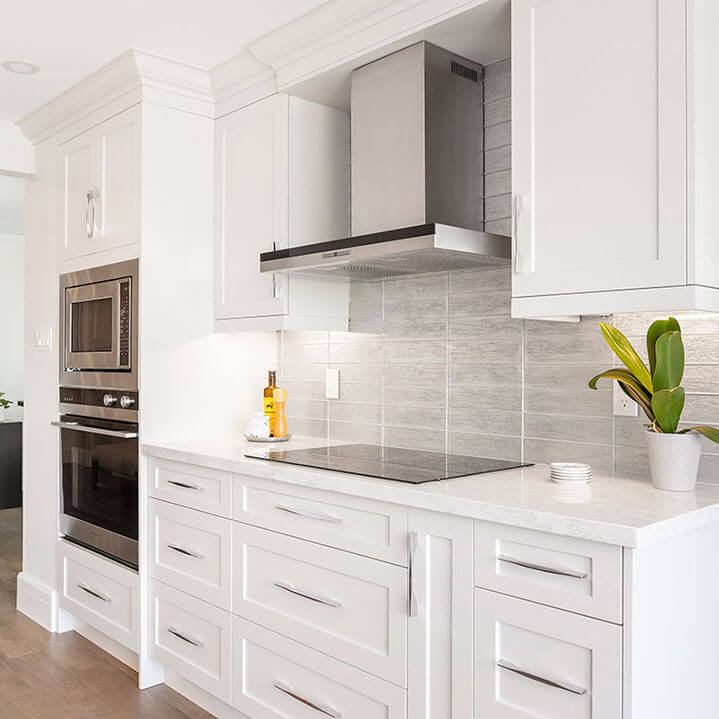 White kitchen with stainless steel vent hood in newly renovated condo.