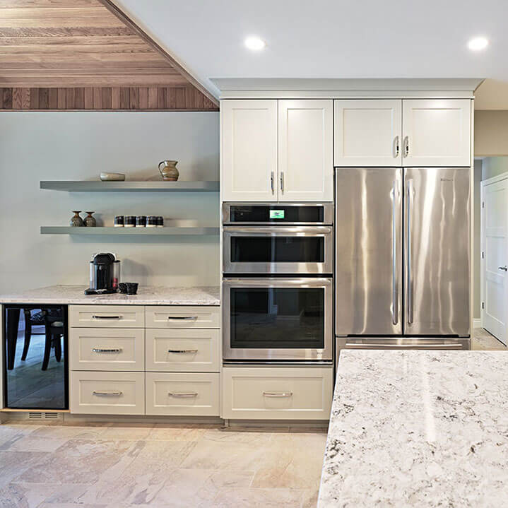 Newly renovated white kitchen with a wall oven, stainless appliances, and a tile floor.